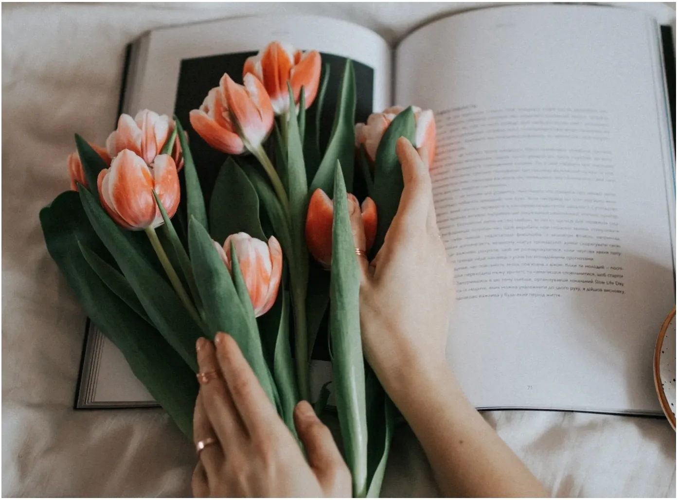 A person holding flowers in front of an open book.