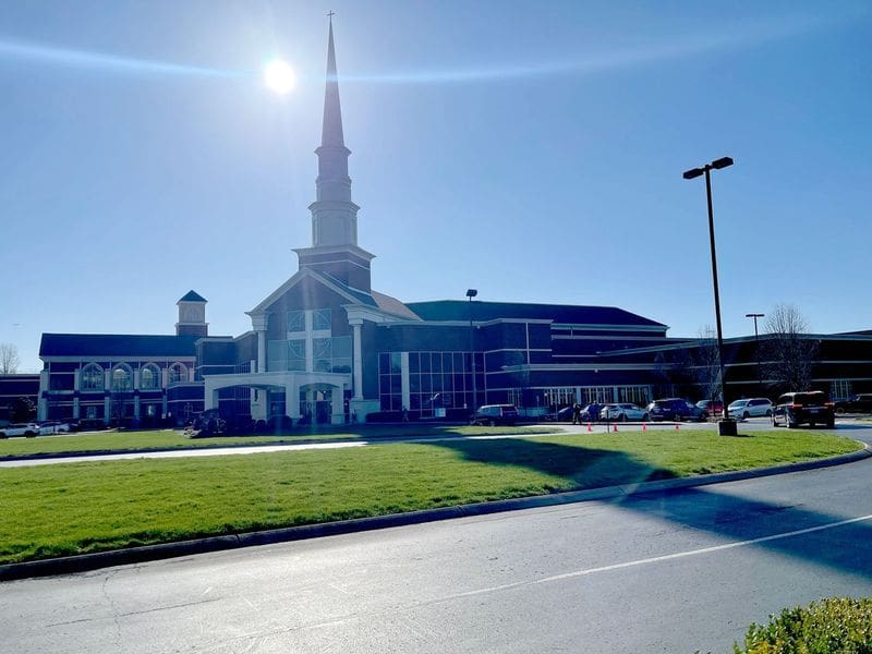 A church with a steeple and grass on the side.