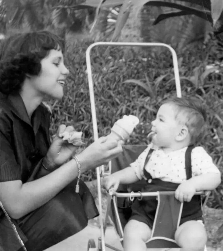 A woman feeding a baby in a high chair.